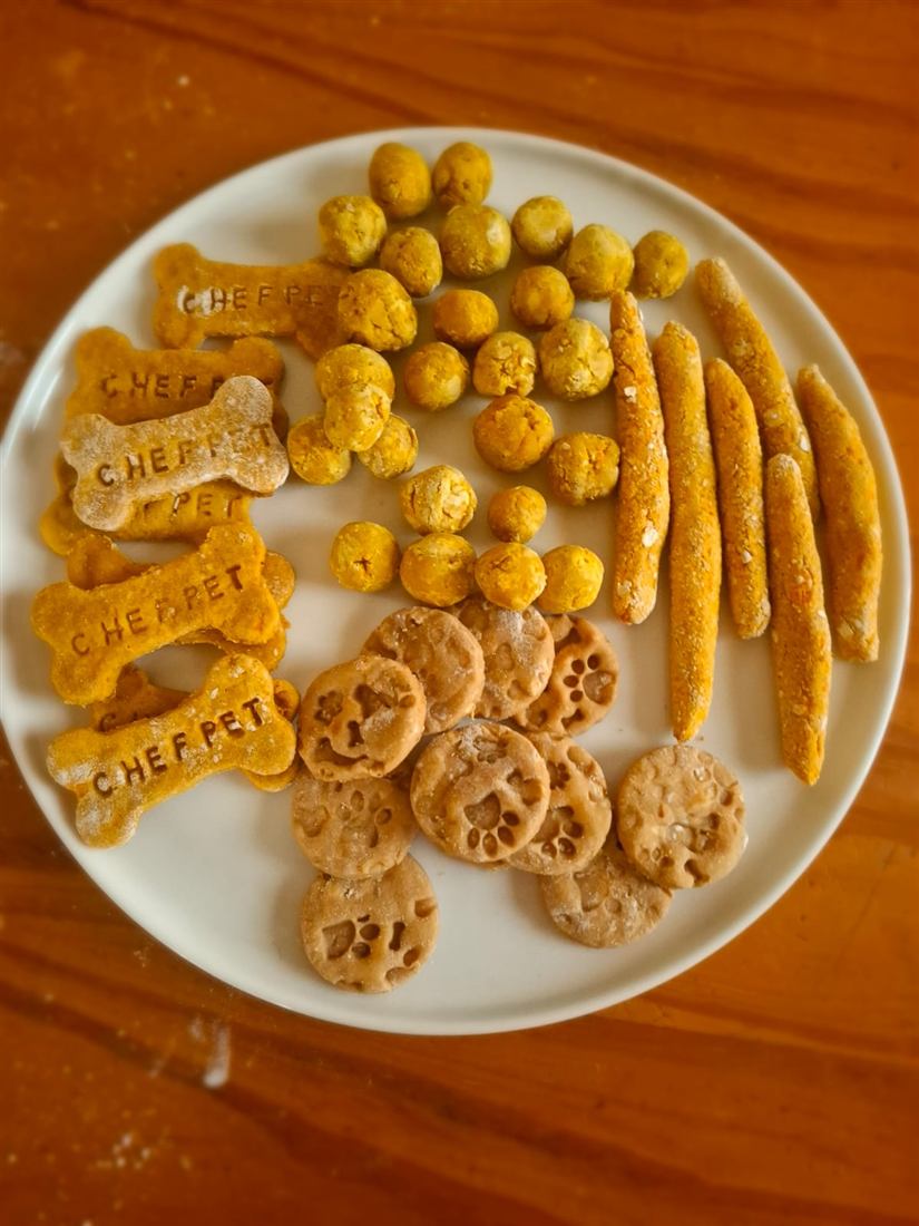 Plato con huesitos grabados con la palabra Chef Pet, scones, palitos y galletas con huellas